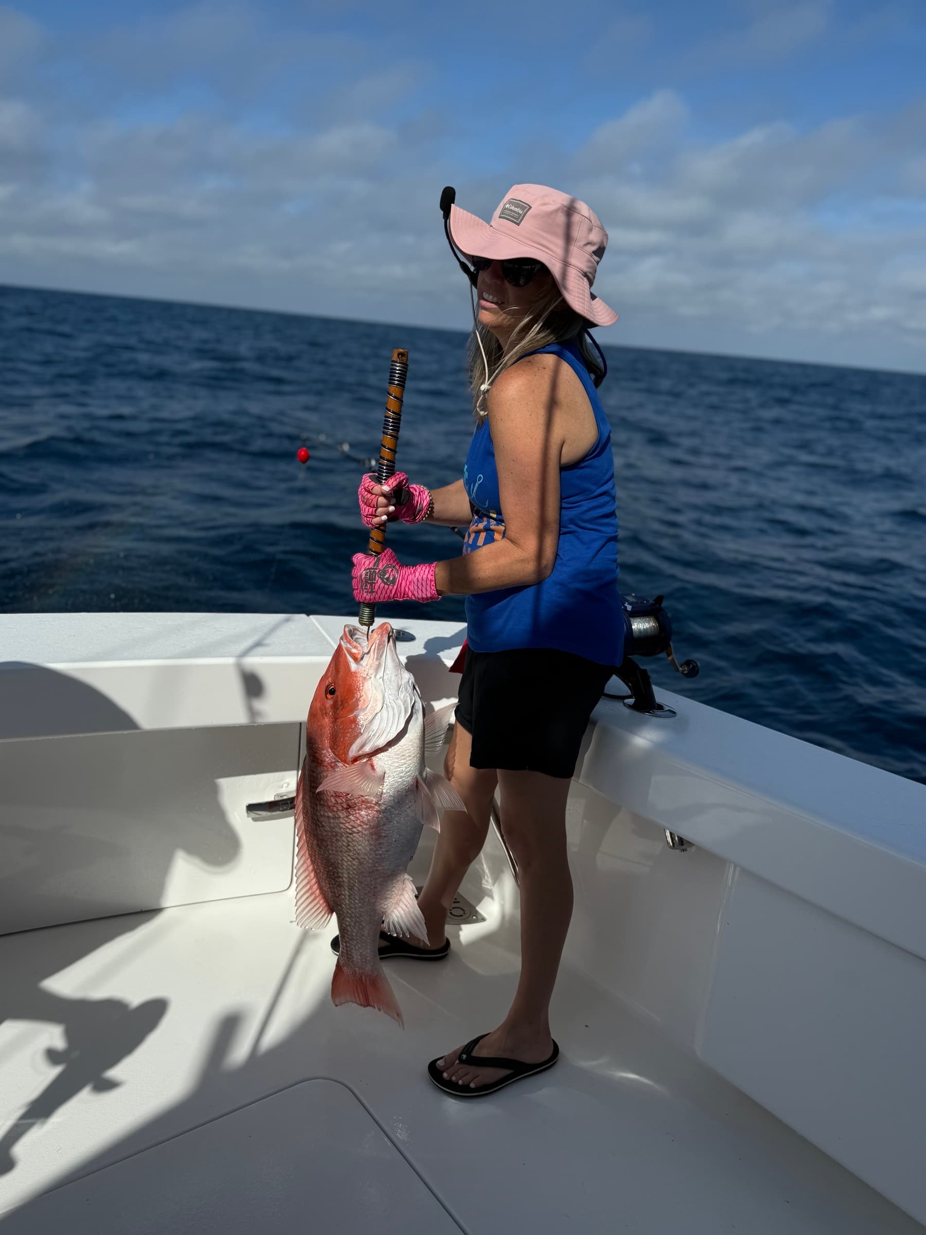 Angler in pink bucket hat holding a trophy red snapper
