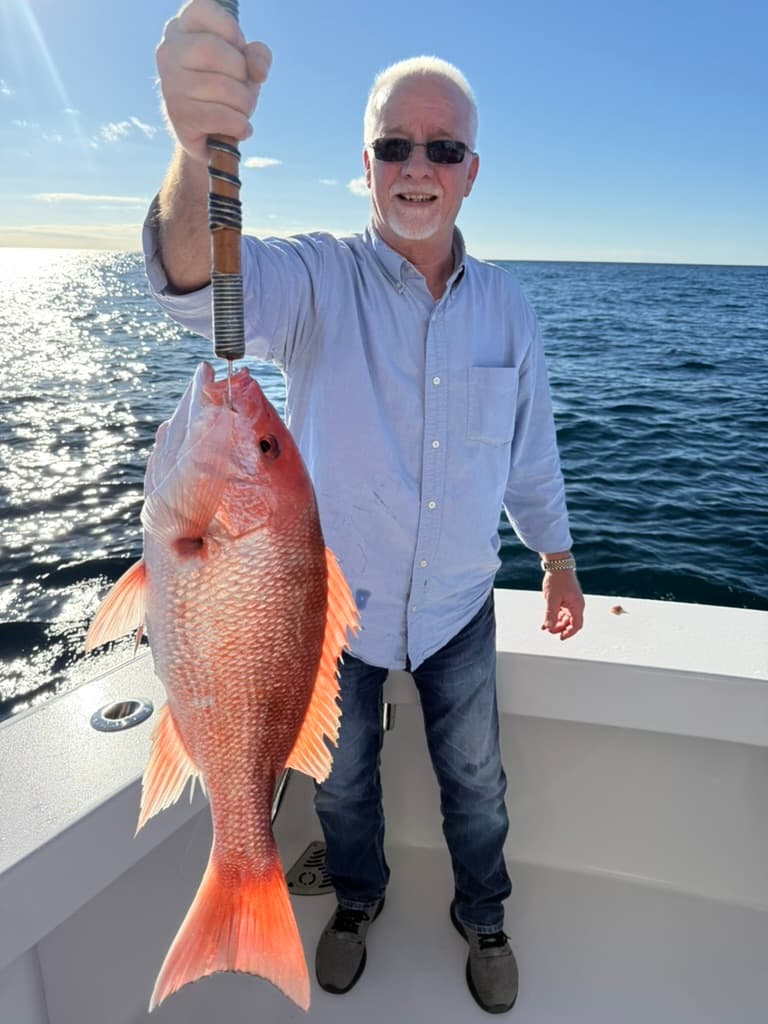 Older angler with a prime red snapper, glassy water